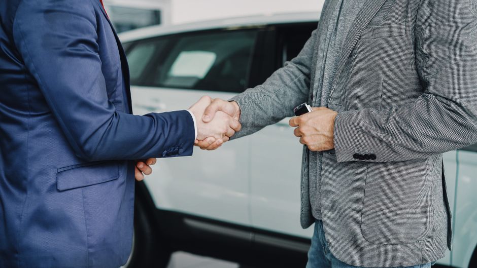 مستشار مبيعات يشرح خيارات التمويل لعميل في وكالة سيارات