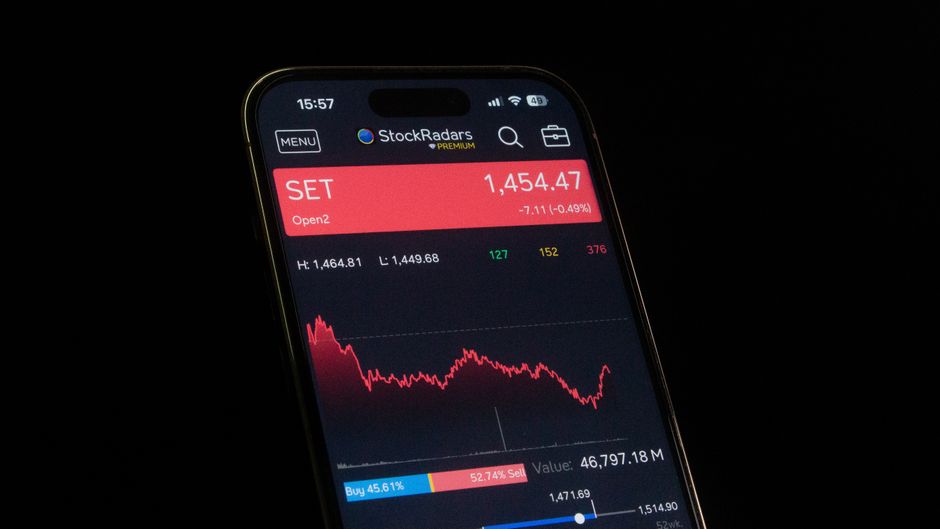 تطبيق تداول مالي على هاتف ذكي بجانب كتاب