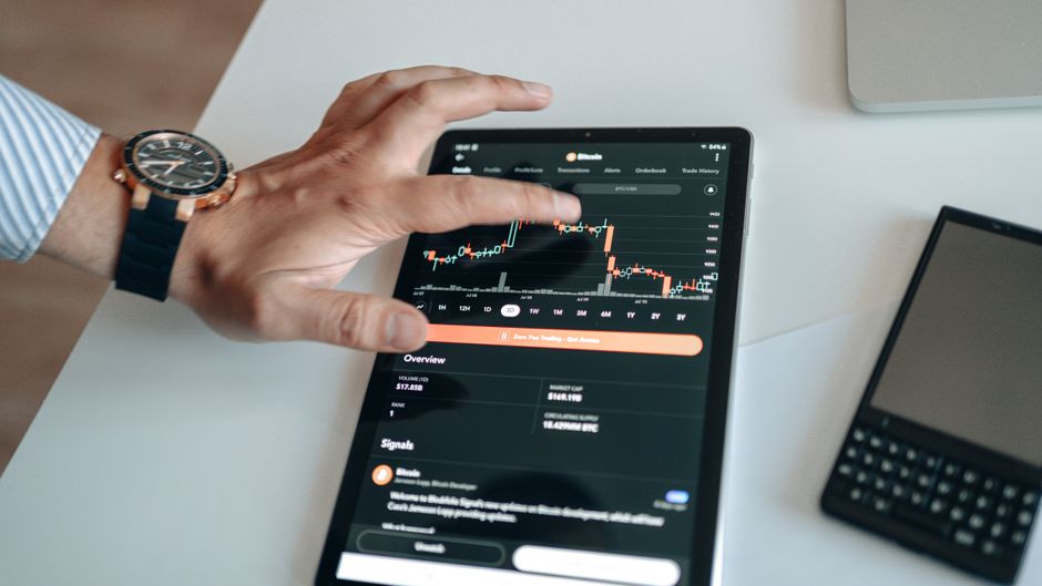 مستثمر يحمل جهازاً لوحياً لمتابعة الأسهم والاستثمارات