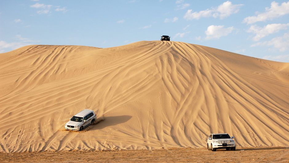 كثبان رملية ذهبية في الصحراء القطرية مع سيارة دفع رباعي