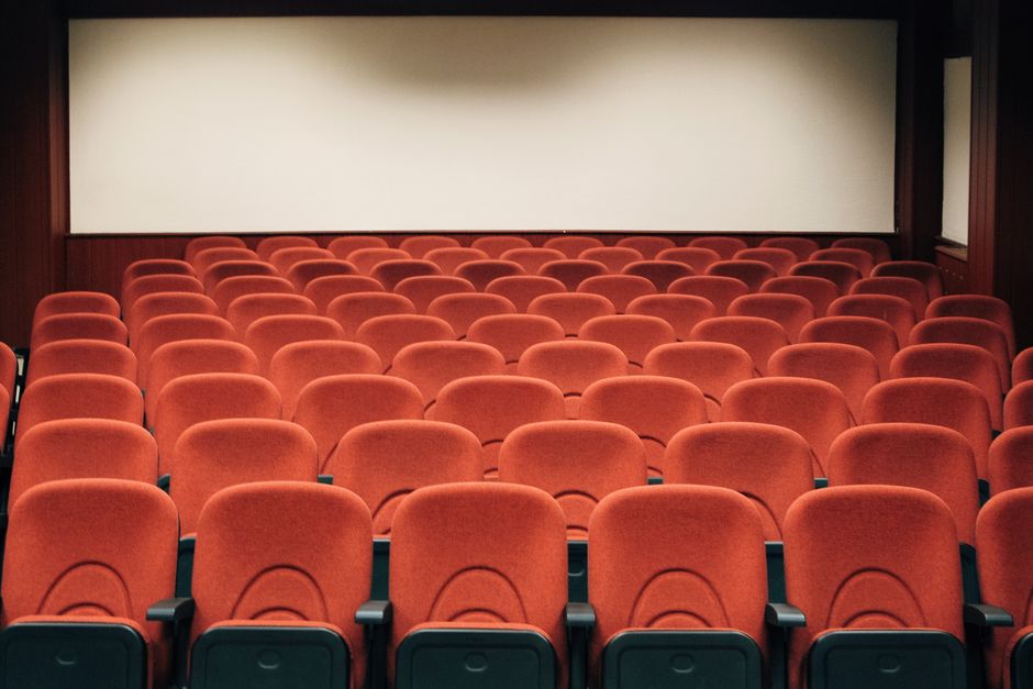 قاعة سينما سعودية بإضاءة خافتة ومقاعد حمراء وشاشة عرض كبيرة