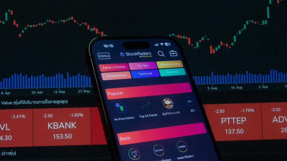 مستثمر يتابع تطبيق تداول الأسهم على هاتفه الذكي