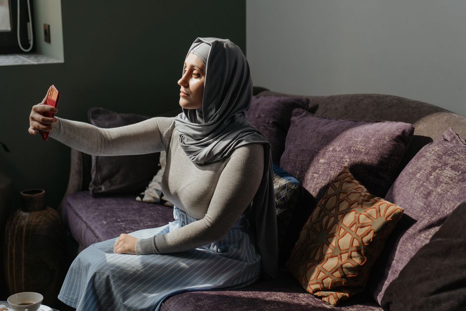 امرأة خليجية مبتسمة تتصفح حساباً على هاتفها الذكي لمتابعة مؤثراتها المفضلة