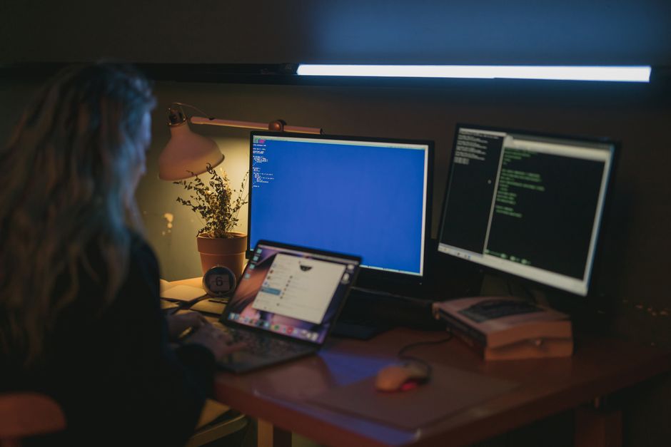 مبرمج يعمل على لابتوب متصل بشاشات متعددة في مكتب حديث